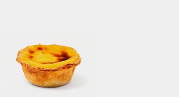 One Portuguese Pastel de Nata pie with custard and cinnamon sticks on a white plate. Pastel de Belem is an iconic cup-shaped pastry with a burnt top and a crispy puff pastry crust. Sweet dessert. photo