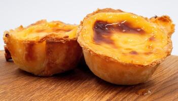 Pastel de nata tarts or Portuguese egg tart on a wooden brown background. Pastel de Belem is a small pie with a crispy puff pastry crust and a custard cream filling. Sweet dessert. photo