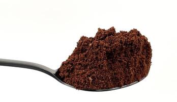 Ground coffee powder in a stainless steel teaspoon isolated on a white background. photo