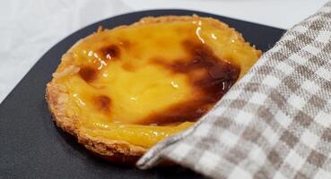 One freshly baked Pastel de nata or Portuguese egg tart in a baking dish. Pastel de Belm is a small pie with a crispy puff pastry crust and a custard cream filling. A small dessert, a cupcake. photo