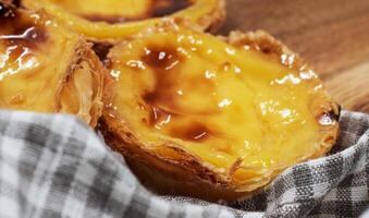 Pastel de nata tarts or Portuguese egg tart on a wooden brown background. Pastel de Belem is a small pie with a crispy puff pastry crust and a custard cream filling. Sweet dessert. photo