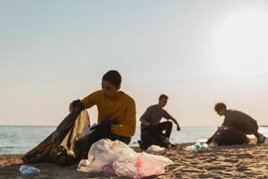 Earth day. Volunteers activists collects garbage cleaning of beach coastal zone. Woman mans with trash in garbage bag on ocean shore. Environmental conservation coastal zone cleaning. Blurred image photo