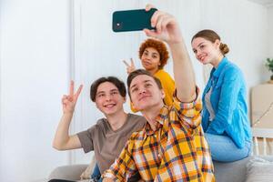 Cheers Funky mood. Happy group of friends make selfie. Man taking photo of friends at party. Group of multiracial young people taking photo on phone. Young people enjoy their company smile have fun