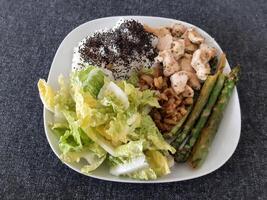 Homemade grilled chicken with rice, green salad and grilled asparagus, served on a white plate. Brocolli seeds on top of the rice photo