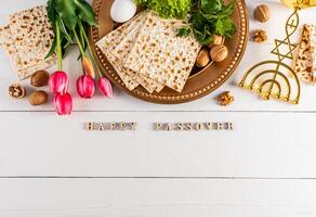 Festive background for the spring holiday of the Jewish Passover. Traditional foods, flowers, minor candlestick. Text of Happy Passover. photo