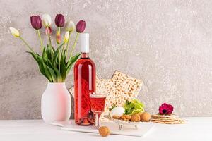 The concept of the spring Jewish holiday of Passover. Traditional matzoth bread, kosher wine, herbs, nuts, egg. Front view. Cement background. photo