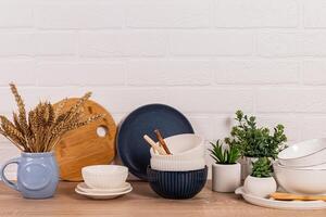 Beautiful kitchen background with different ceramic bowls,potted indoor plants. Front view. White brick wall. photo