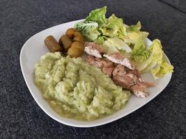 Homemade grilled chicken with zucchini stew, green salad and cucumber pickles served on a white plate photo