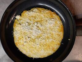 Fried breakfast omelette with cheese, on a black iron pan photo