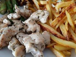 Homemade grilled chicken with french fries, asparagus, grilled chopped eggplant and green salad, served on a white plate photo