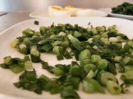 rebanado verde cebollas servido en un blanco plato foto