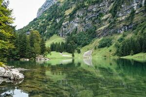 Seealpsee mountain lake reflection in Alpstein mountain range during summer at Appenzell, Switzerland photo