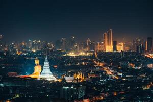 Cityscape of Bangkok night scene with building exterior, buddha in temple and department store glowing in downtown photo