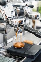 Espresso machine making hot coffee into dosing cup in coffee shop photo