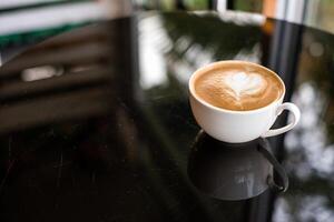 café latté corazón forma en blanco taza en mesa foto
