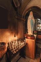 estatua madre Virgen María Orando y luz de una vela altar en cristiano chruch foto