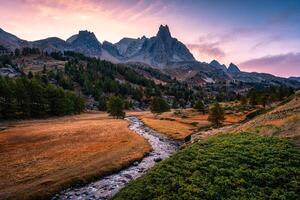 Sunset over Claree Valley with Main De Crepin peak and river flow through in larch forest during autumn at French Alps, France photo