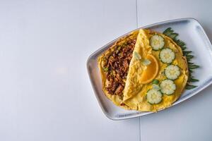 Omelet filled beef fried with vegetable on white table photo