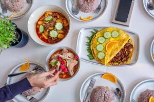 Hand reaching to bowl with egg omelet and spicy soup on the table photo