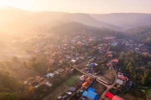 Sunrise over Thai tribe village in foggy with wild himalayan cherry tree blooming at Ban Rong Kla, Thailand photo