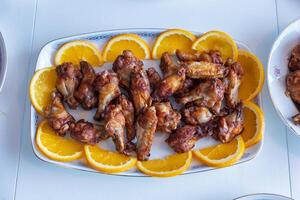 Chicken drumsticks fried and grilled with orange slices in plate photo