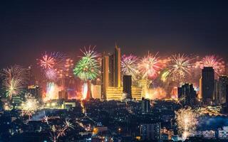 New year festival with firework display glowing over department store, illuminated building in downtown during midnight time at Bangkok, Thailand photo