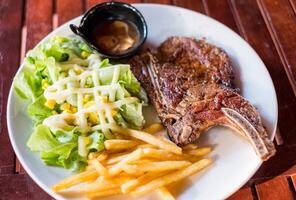 A la parrilla Cerdo costillas filete bien hecho con francés papas fritas y vegetal foto