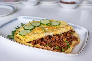 Omelet filled beef fried with vegetable on white table photo