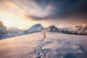 alpinista caminando con huella en nieve tormenta y amanecer terminado Nevado montaña en senja isla foto