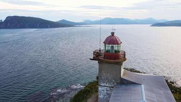 Aerial view of the old Balyuzek lighthouse on the rocky coast of the sea video