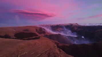 Majestic northern mountains under bright purple sky aerial top view. Purple sky illuminating evening enhancing mountain beauty Purple sky over mountains symbol of nature's wonder winter spectacle. video