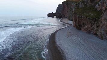 Aerial view of beautiful sea stack and dark cliffs in sunset. Calm seascape video