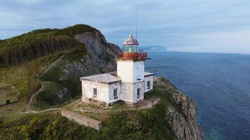 Aerial view of the old Balyuzek lighthouse on the rocky coast of the sea video