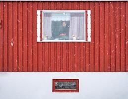 Exterior of red hardwood wall and window frame of fishing nordic house on winter season photo