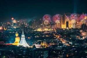 Bangkok night scene with big buddha in temple and firework display show over department store in crowded downtown photo