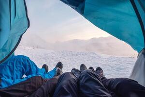 Climber legs resting in a tent among the blizzard on mountain photo