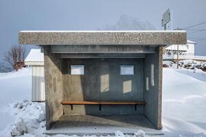 Nobody in concrete shelter bus stop and bench in snowing day photo