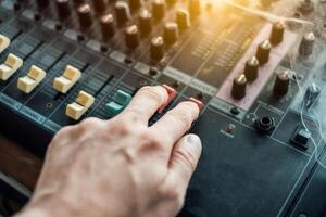 Close-up hand adjusting mixer sound on audio panel photo