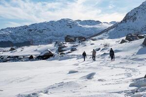 Tourists group walking on snow hill at sunny photo