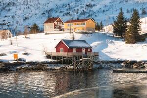 Scandinavian red house with wooden jetty on coastline photo