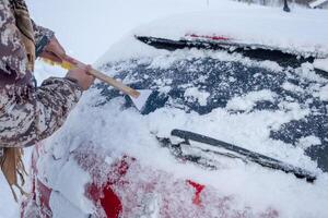 Hand using web scraping snow on car rear windscreen photo