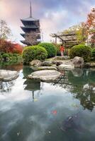 Ancient wood pagoda with fish in autumn garden at Toji temple photo
