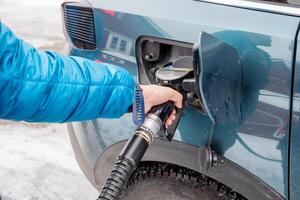 Hand hold refueling nozzle self-service in fuel tank at fuel station photo