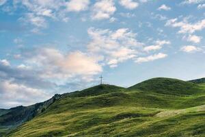 Wooden cross on top of mountain and bright sky in Swiss Alps at Switzerland photo