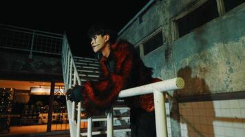 Man sitting on railing at night with urban background, contemplating. video