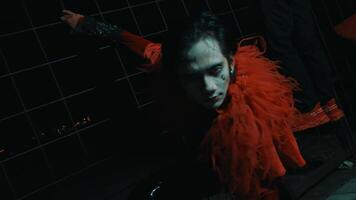 Person with dramatic makeup and red attire posing in a dark, moody setting. video