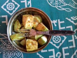 Close up view of delicious asian food, guava mixed with tasty and hot mustard sauce, locally known as kasund,i kept in a bowl with a spoon, guava is cut into small pieces. photo