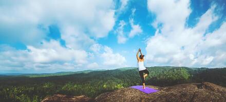 Asian women relax in the holiday. Travel relax.  Play if yoga. On the Moutain rock cliff. Nature of mountain forests in Thailand photo