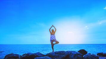 las mujeres asiáticas se relajan en las vacaciones. viajar relajarse. jugar si yoga. sobre las rocas junto al mar. en el verano. tailandia foto