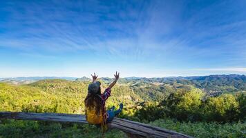 joven mujer turistas con mochilas contento a viaje ella elevado su manos y disfrutando naturaleza paisaje vista. foto